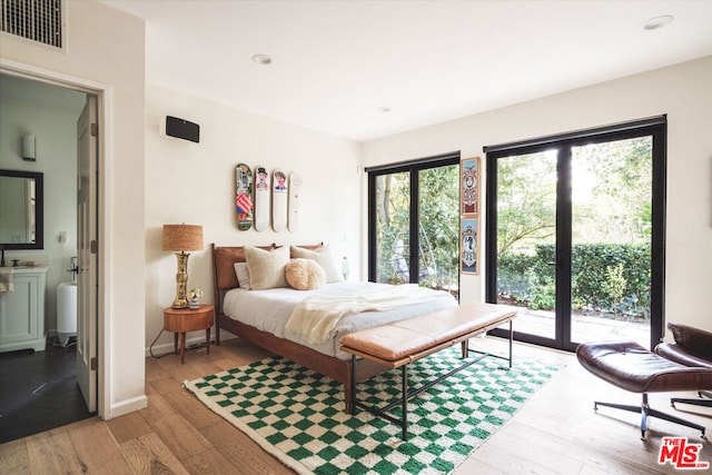 bedroom with light wood-type flooring, access to outside, and ensuite bath