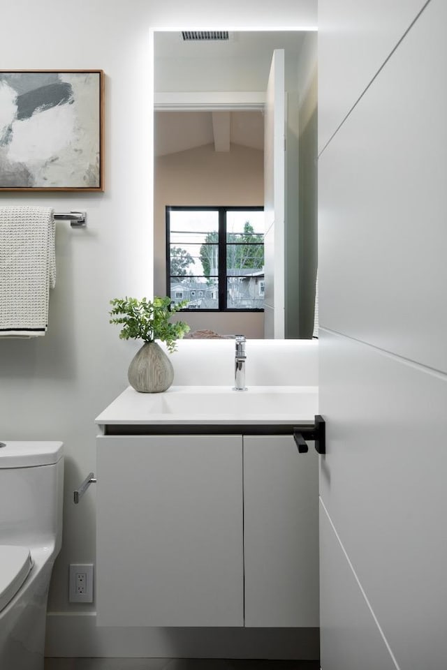 bathroom featuring vanity, vaulted ceiling with beams, and toilet