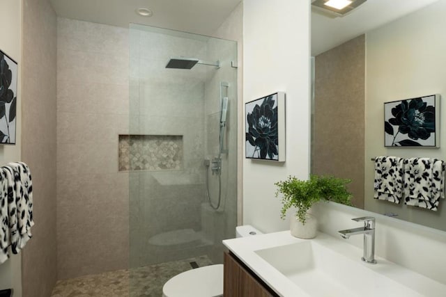 bathroom featuring vanity, toilet, and a tile shower