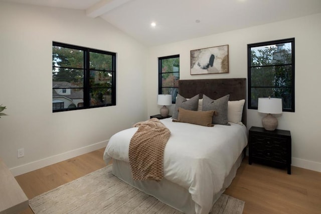 bedroom with lofted ceiling with beams and light wood-type flooring