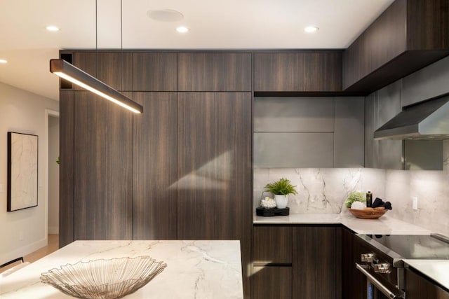 kitchen with light stone counters, dark brown cabinetry, stainless steel range with electric cooktop, and backsplash