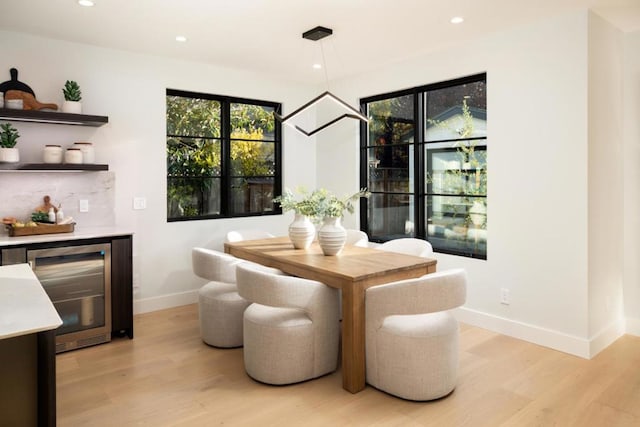 dining room with beverage cooler and light hardwood / wood-style flooring