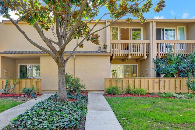 view of front of property with a balcony and a front lawn