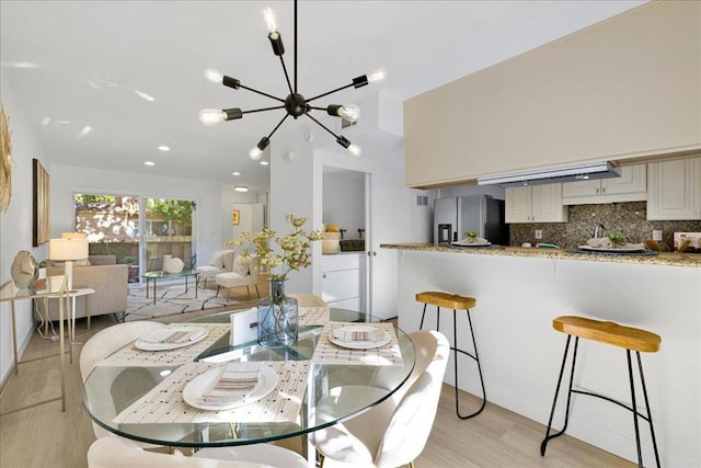 dining area with separate washer and dryer, an inviting chandelier, and light hardwood / wood-style floors