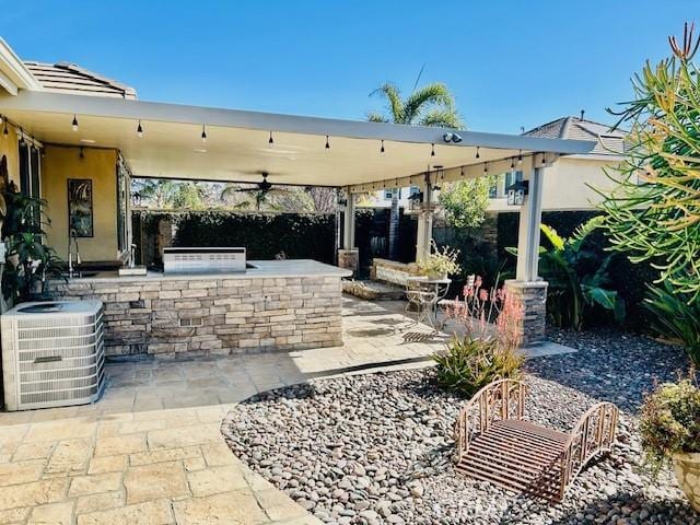 view of patio with ceiling fan, an outdoor kitchen, central AC unit, and an outdoor bar