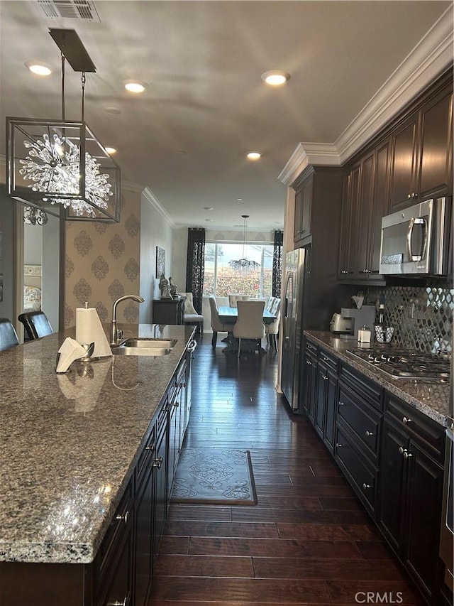 kitchen with dark stone countertops, sink, hanging light fixtures, and appliances with stainless steel finishes