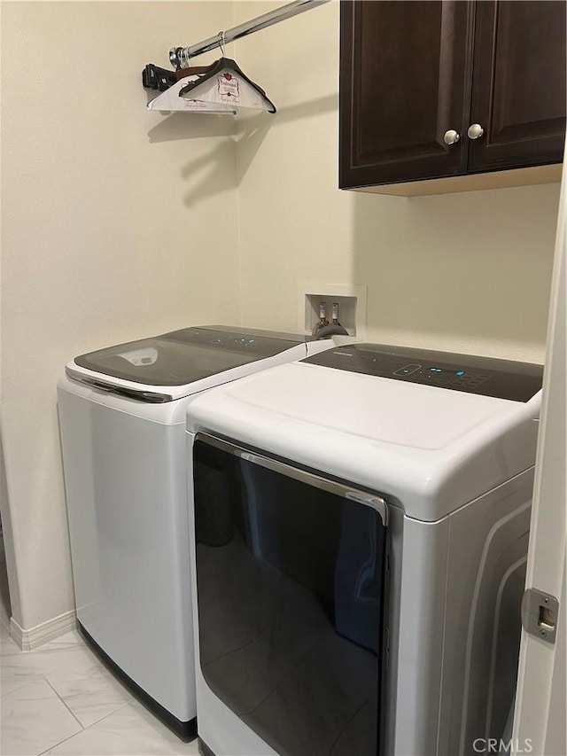 clothes washing area featuring cabinets and separate washer and dryer