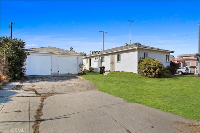 view of front of house with concrete driveway, a front yard, stucco siding, a garage, and an outbuilding