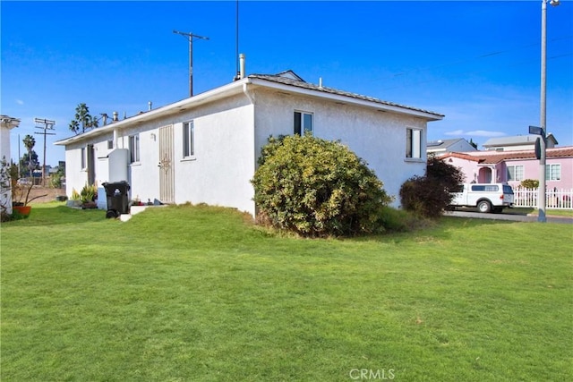 view of side of home featuring stucco siding and a lawn