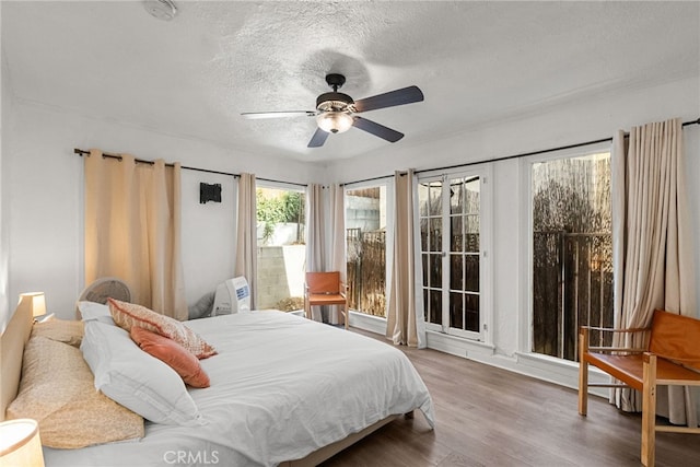 bedroom with ceiling fan, light hardwood / wood-style flooring, and a textured ceiling