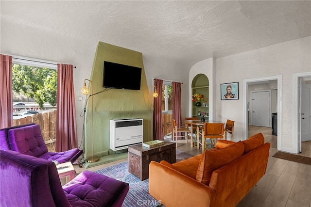 living room featuring a textured ceiling, heating unit, and light wood-type flooring