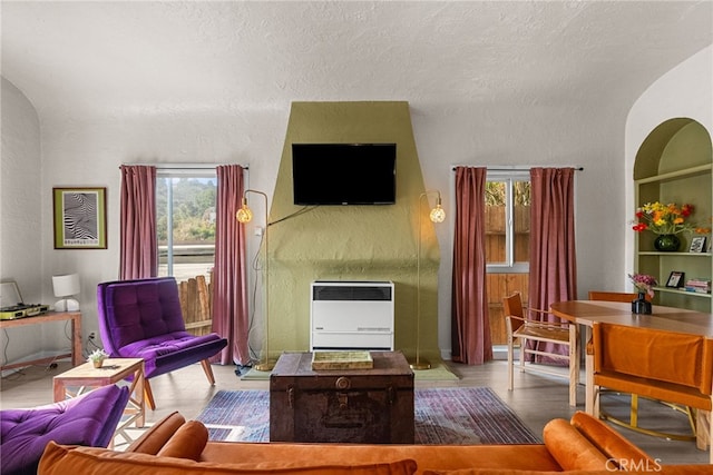 living room featuring heating unit, built in features, and a textured ceiling