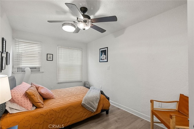 bedroom featuring ceiling fan, hardwood / wood-style floors, and a textured ceiling