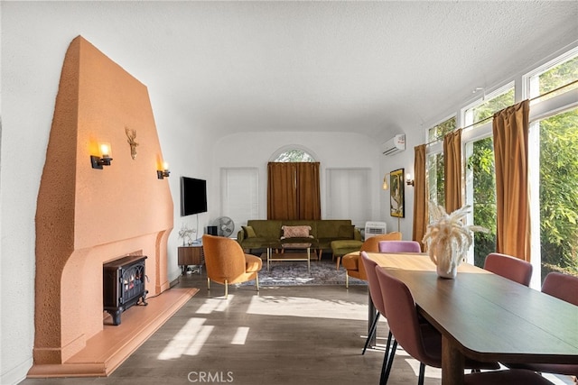 dining space with wood-type flooring, a wall mounted AC, and a textured ceiling