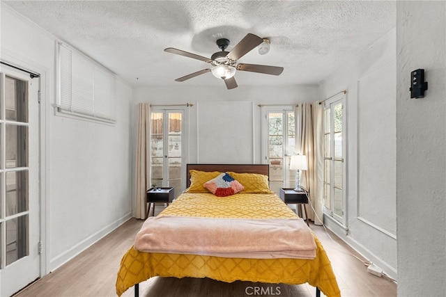 bedroom with ceiling fan, light hardwood / wood-style floors, and a textured ceiling