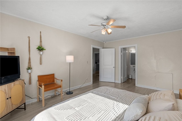 bedroom featuring ceiling fan, ensuite bath, a textured ceiling, and light wood-type flooring