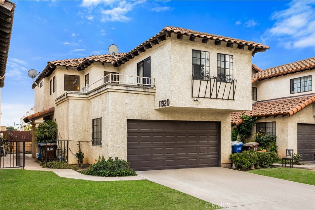 mediterranean / spanish-style house with a balcony, a garage, and a front lawn