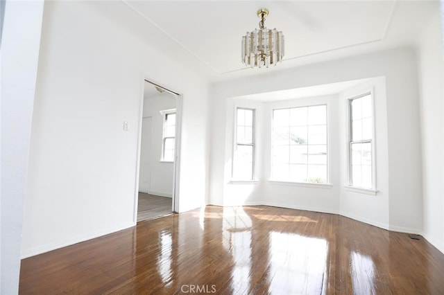 empty room with dark hardwood / wood-style floors and a chandelier