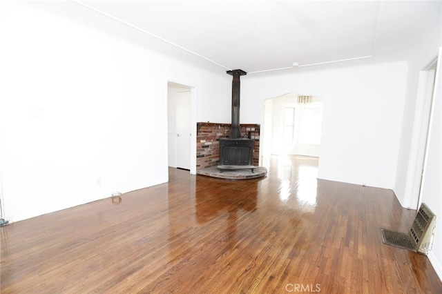 unfurnished living room with a wood stove and dark wood-type flooring