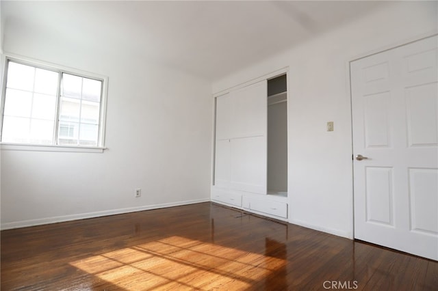 unfurnished bedroom with dark hardwood / wood-style floors and a closet