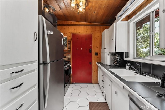 kitchen with lofted ceiling, white cabinetry, stainless steel appliances, wooden ceiling, and wood walls