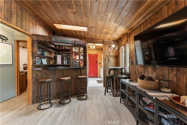 bar featuring wooden ceiling, light hardwood / wood-style floors, and wood walls