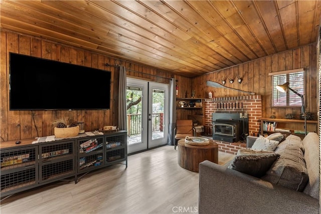 living room featuring wooden walls, light wood-type flooring, a wood stove, and wooden ceiling