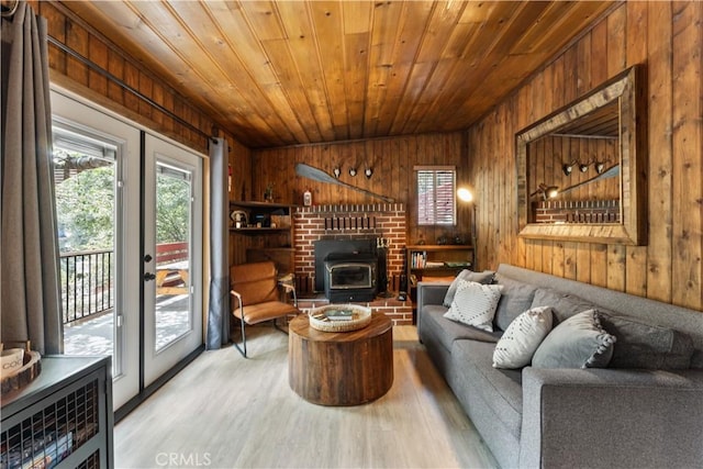 living room with wood ceiling, light hardwood / wood-style flooring, a wood stove, and wood walls