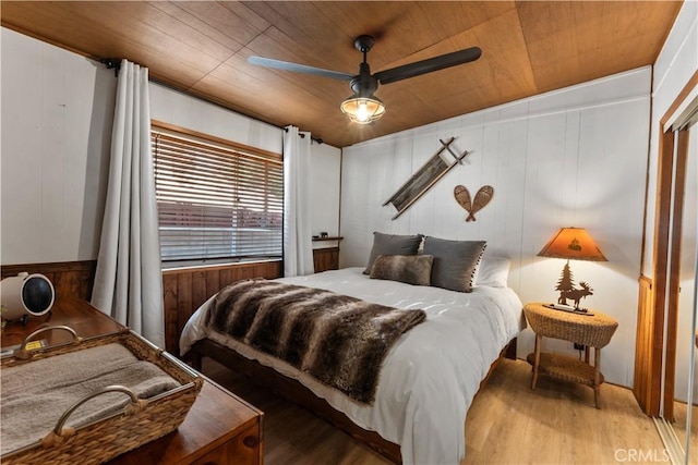 bedroom featuring wooden walls, hardwood / wood-style floors, wooden ceiling, and ceiling fan