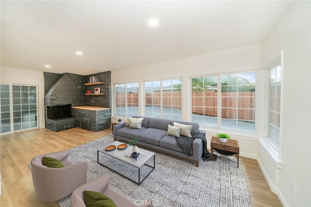 living room with wood-type flooring, plenty of natural light, and a stone fireplace