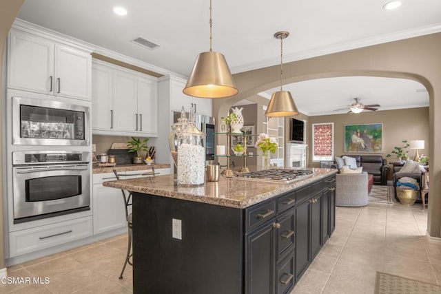 kitchen with white cabinetry, hanging light fixtures, a center island, light stone counters, and stainless steel appliances