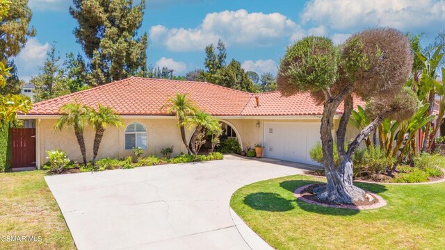 mediterranean / spanish home with a garage and a front lawn