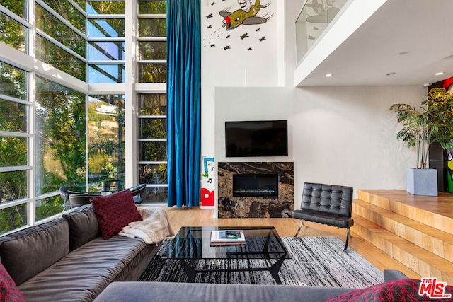 living room featuring a premium fireplace, a towering ceiling, and hardwood / wood-style floors