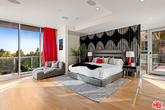 bedroom featuring access to exterior, wood-type flooring, and floor to ceiling windows