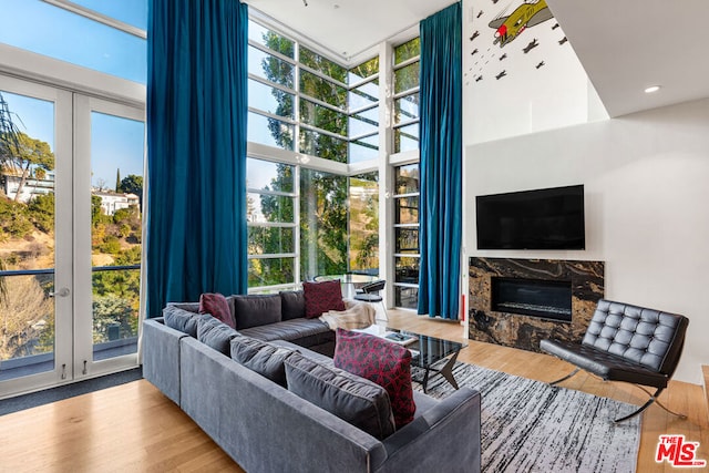 living room featuring expansive windows, a healthy amount of sunlight, a high end fireplace, and light hardwood / wood-style floors