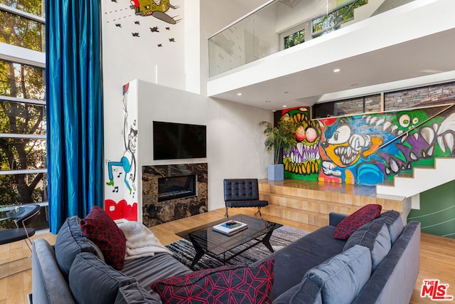 living room with hardwood / wood-style flooring, a high end fireplace, and a high ceiling