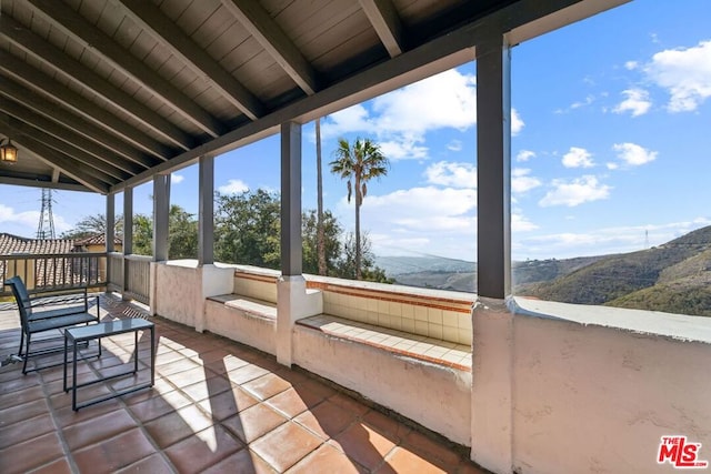 sunroom featuring a mountain view and vaulted ceiling with beams