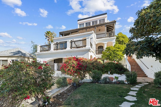 exterior space with a balcony and a front yard