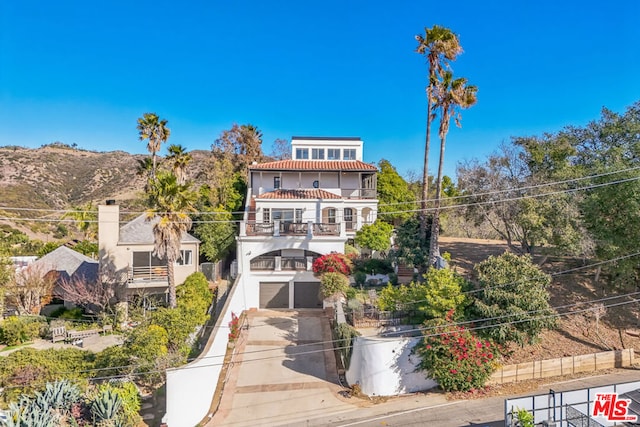 rear view of house featuring a mountain view, a garage, and a balcony