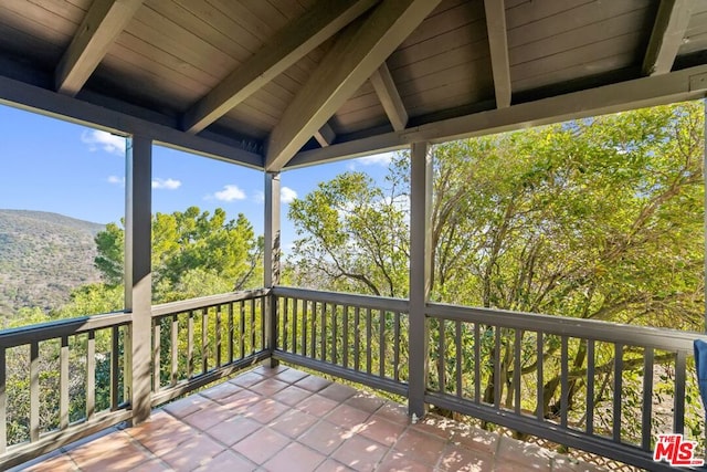 unfurnished sunroom with a mountain view and lofted ceiling with beams