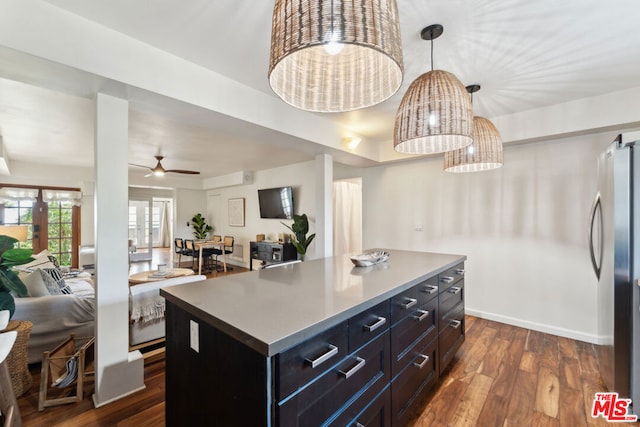 kitchen featuring dark wood-type flooring, stainless steel refrigerator, a kitchen island, pendant lighting, and ceiling fan