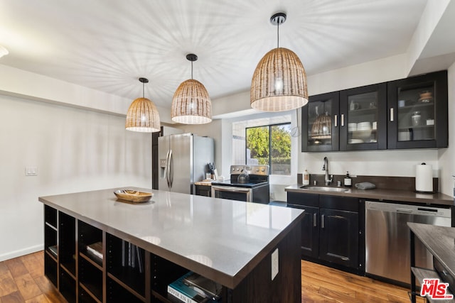 kitchen with pendant lighting, sink, a center island, stainless steel appliances, and light wood-type flooring