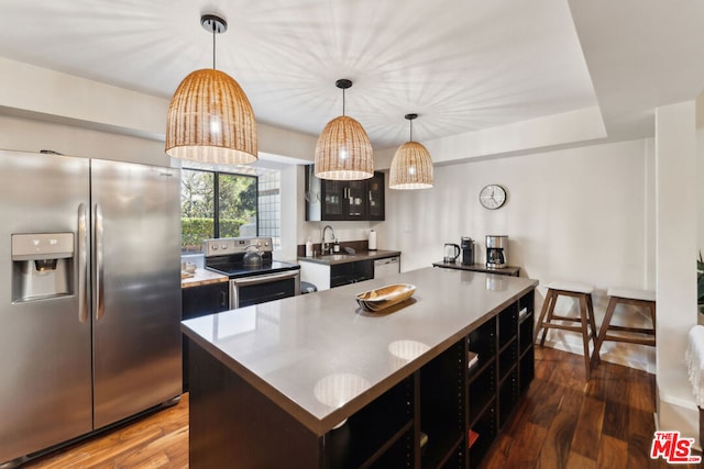 kitchen featuring stainless steel appliances, dark hardwood / wood-style floors, a center island, and hanging light fixtures