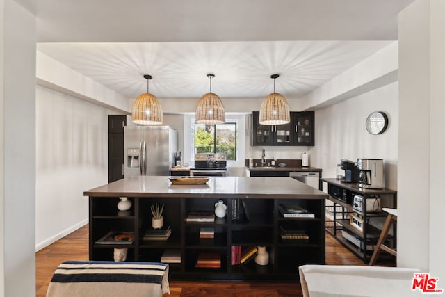 kitchen with sink, a center island, pendant lighting, stainless steel appliances, and hardwood / wood-style floors