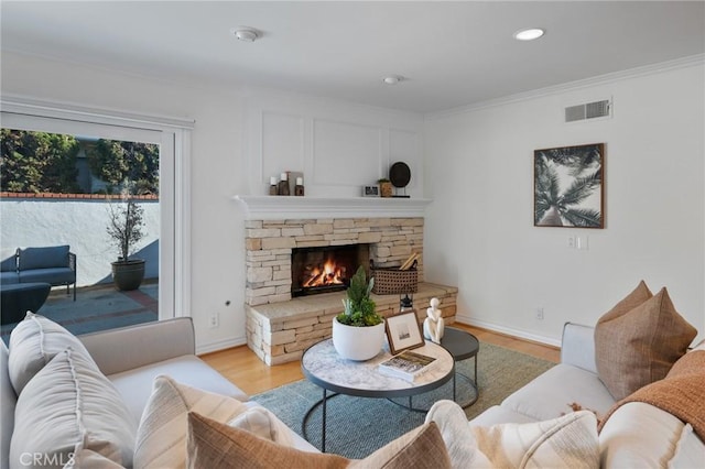 living room featuring a fireplace, light hardwood / wood-style flooring, and ornamental molding