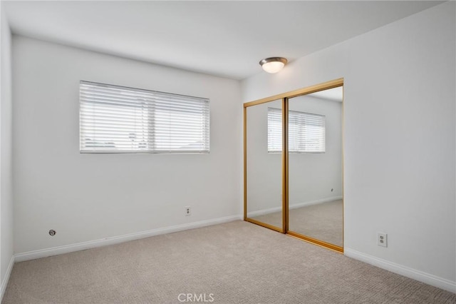 unfurnished bedroom featuring light carpet and a closet