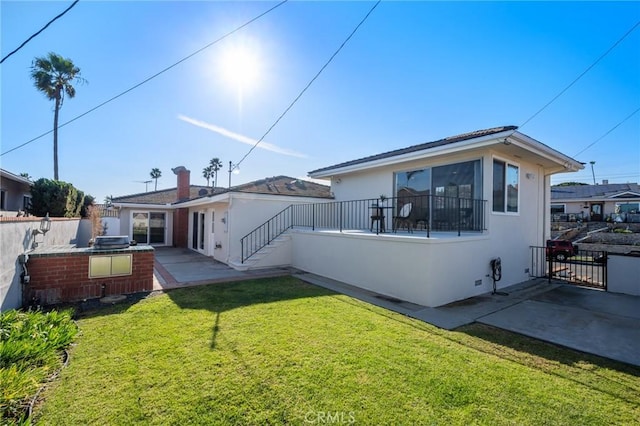 rear view of property with a yard, a patio, and an outdoor kitchen