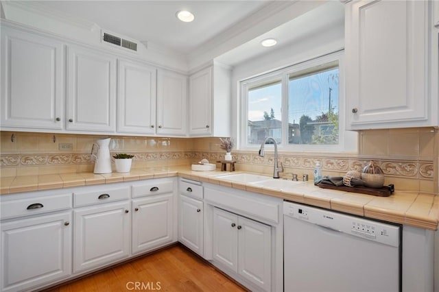 kitchen featuring white dishwasher, tile counters, and white cabinets