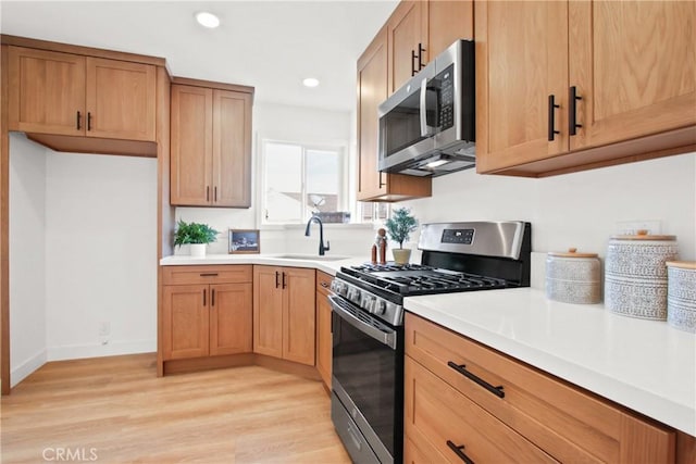 kitchen featuring appliances with stainless steel finishes, sink, and light wood-type flooring