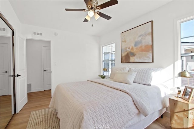 bedroom with ceiling fan, multiple windows, and light wood-type flooring